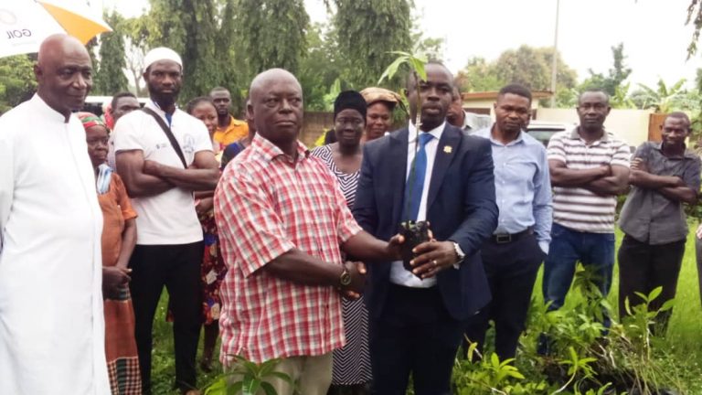 Mr Kumi (in suit) presenting seedlings to a farmer