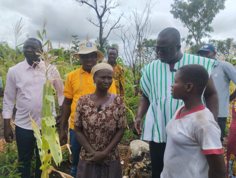 Minister of Agriculture (in smock) posed with Minister of Finance (in pink) and affected farmers 