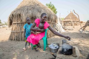 A farmer with her two children, preparing a meal using a fuel-efficient cooking stove in Nasir County, Upper Nile State, South Sudan.©FAO Photo/ Mayak Akuot